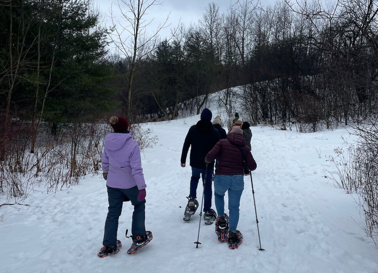 John MacDonald Architect staff walking through Huron Natural Area on snowshoes